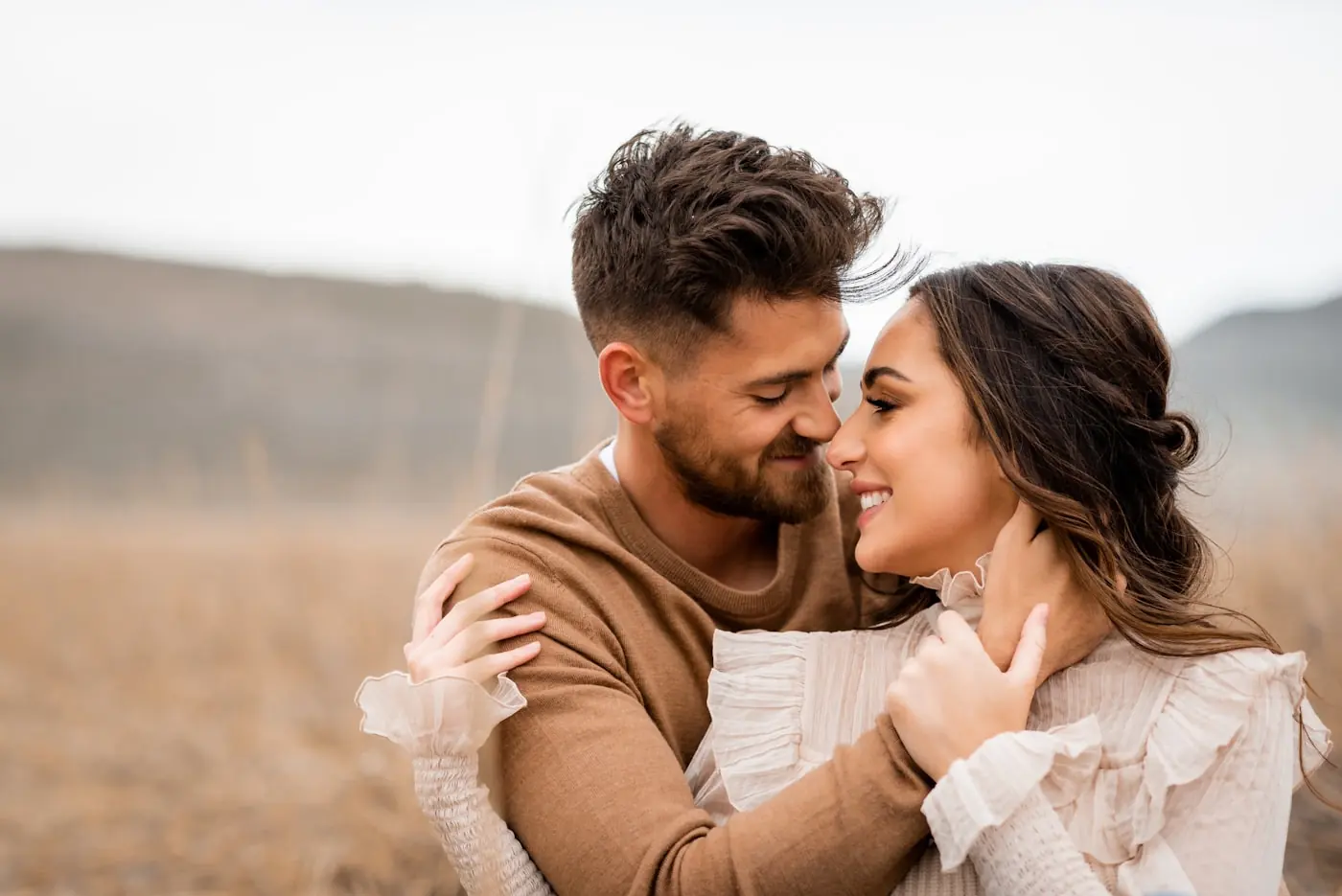 A couple holding each other close, smiling, foreheads almost touching