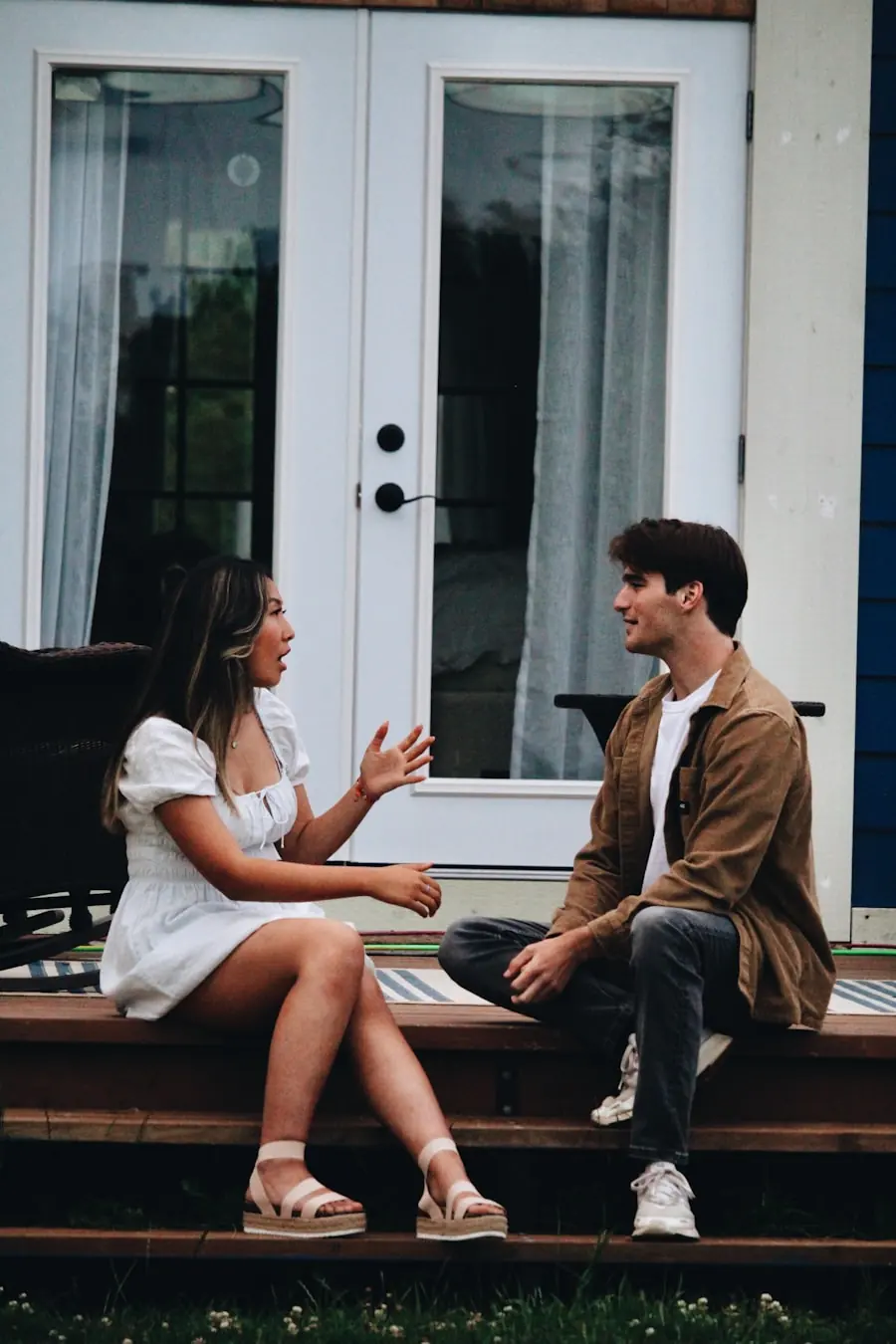 A couple sitting on porch steps, mid-conversation