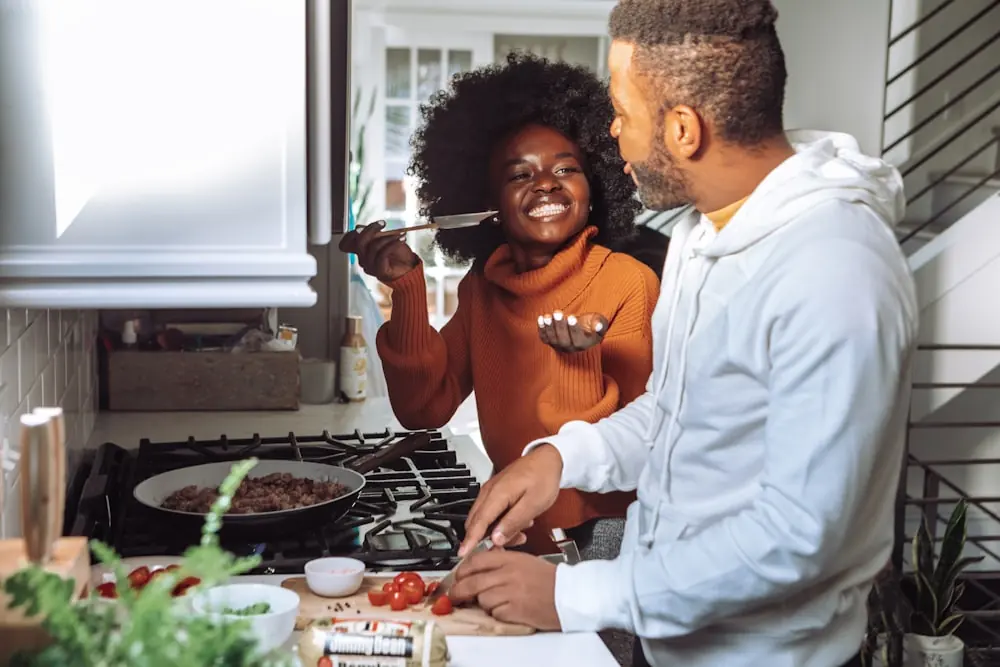 A couple cooking together in their kitchen, laughing